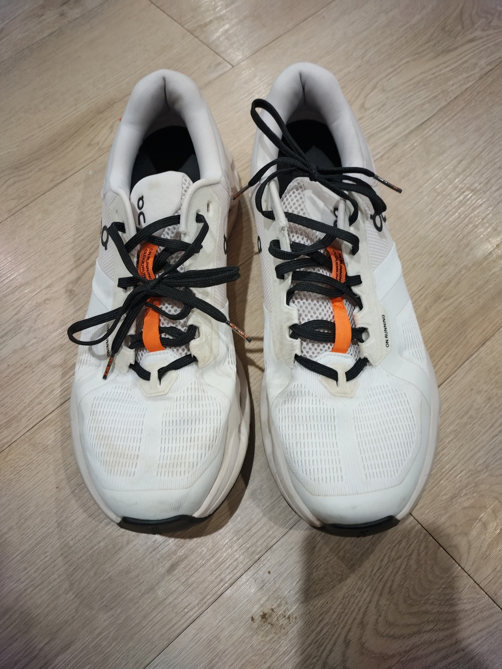 On Running Men’s White Athletic Shoes with Black Laces and Orange Tongue Accent